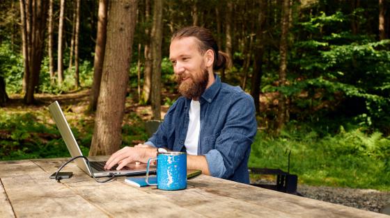 man working on laptop in wooded area
