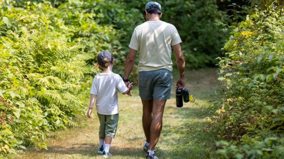 Counselor and Camper walking away in green forest