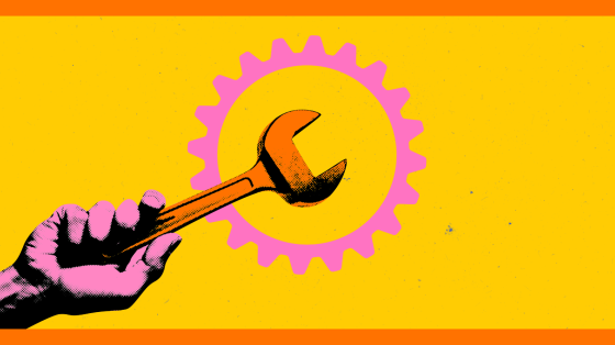 Hand holding wrench in front of a gear