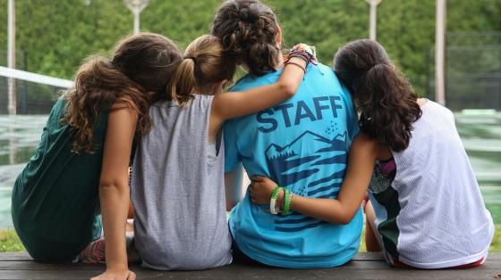 campers with their arms around a camp staff member