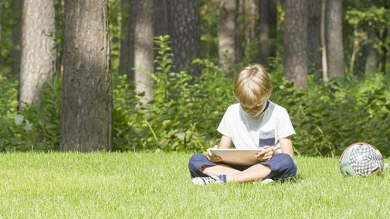 Young boy sitting outside with a tablet