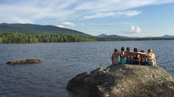 campers sitting on rock looking out over lake