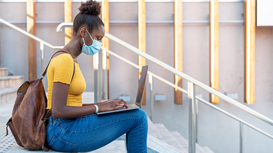 college student wearing mask with laptop