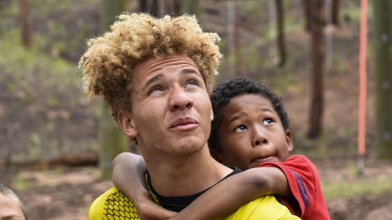 camper hanging on to counselor's shoulders