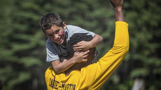 Counselor holding camper with his fist in the air