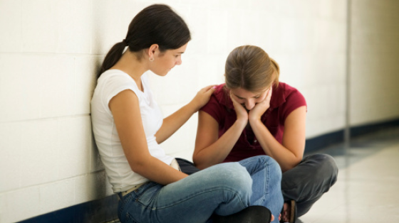 Young adult consoling depressed teenager