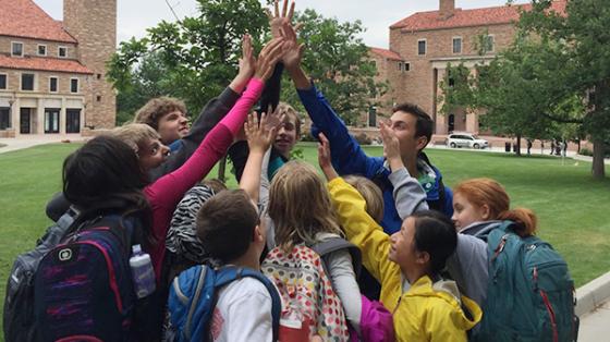 Campers and staff forming a high-five pyramid