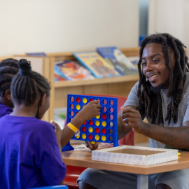 Counselor and campers playing connect four