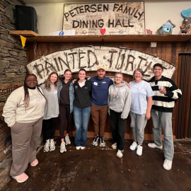 Camp staff standing in front of dining hall sign