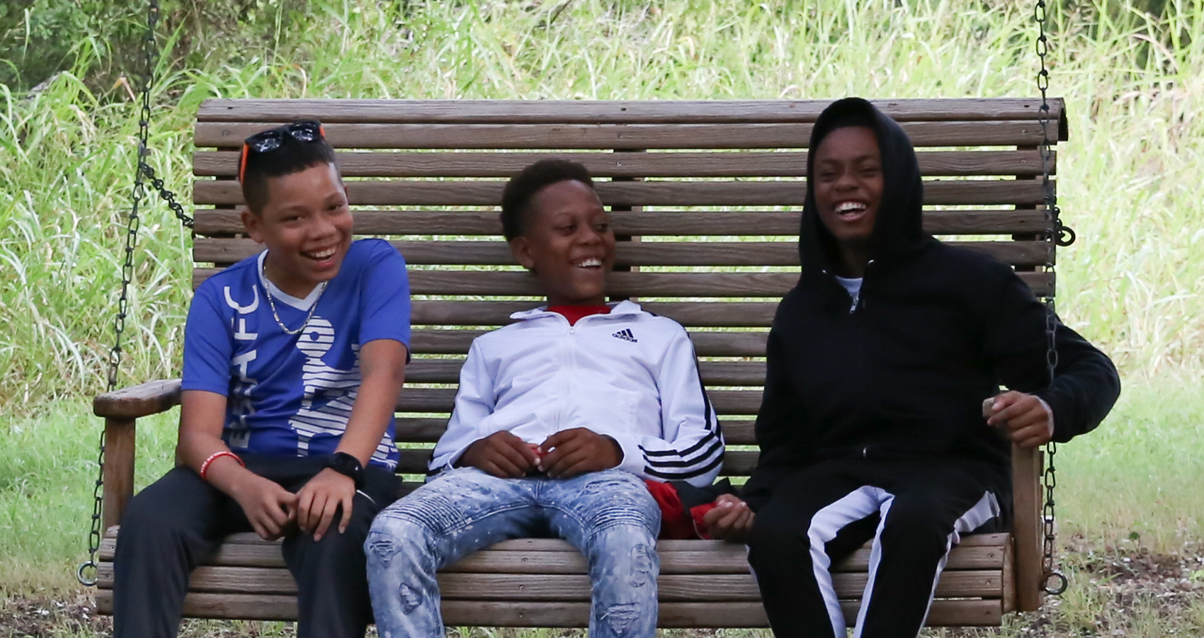 Three campers sitting on swing smiling