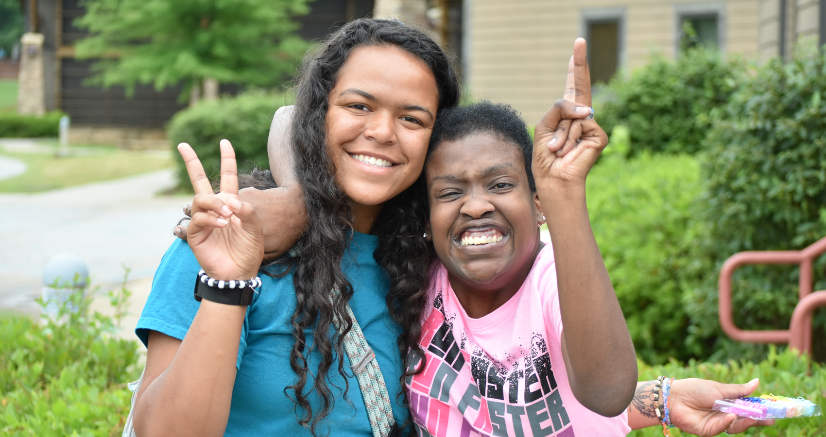 Counselor and camper smiling with peace sign hands