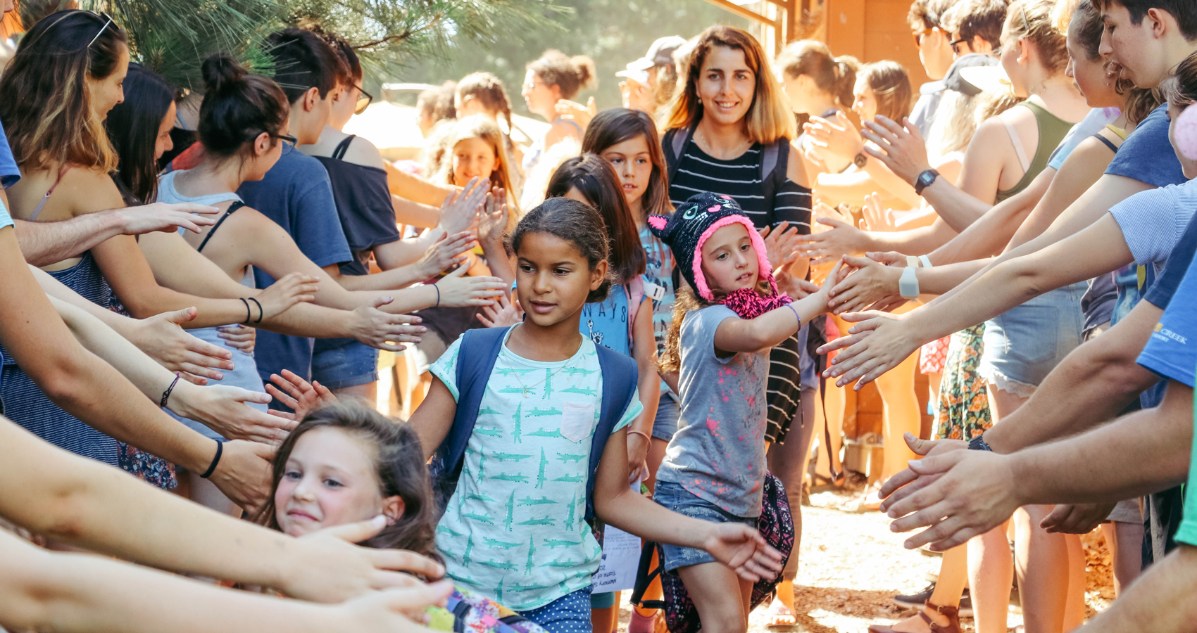 Line of campers high fiving through tunnel of staff