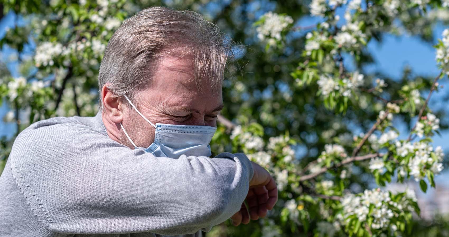 stock photo of man in mask sneezing outdoors