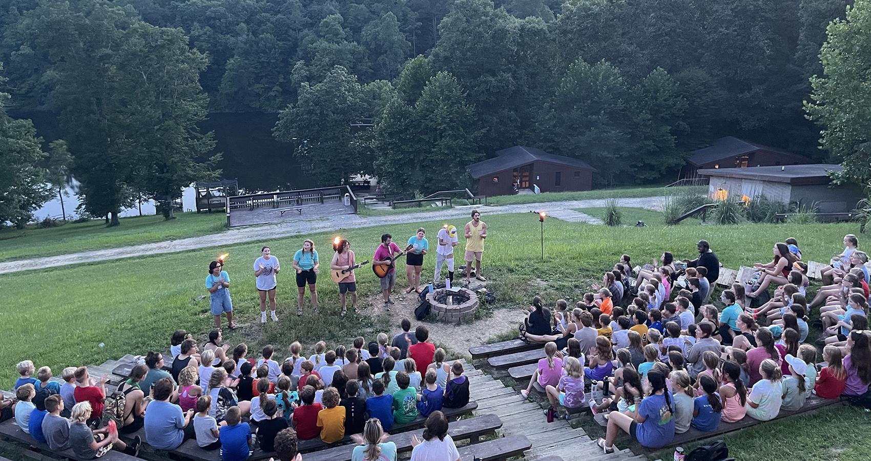 campers sitting on benches in front of a group of staff