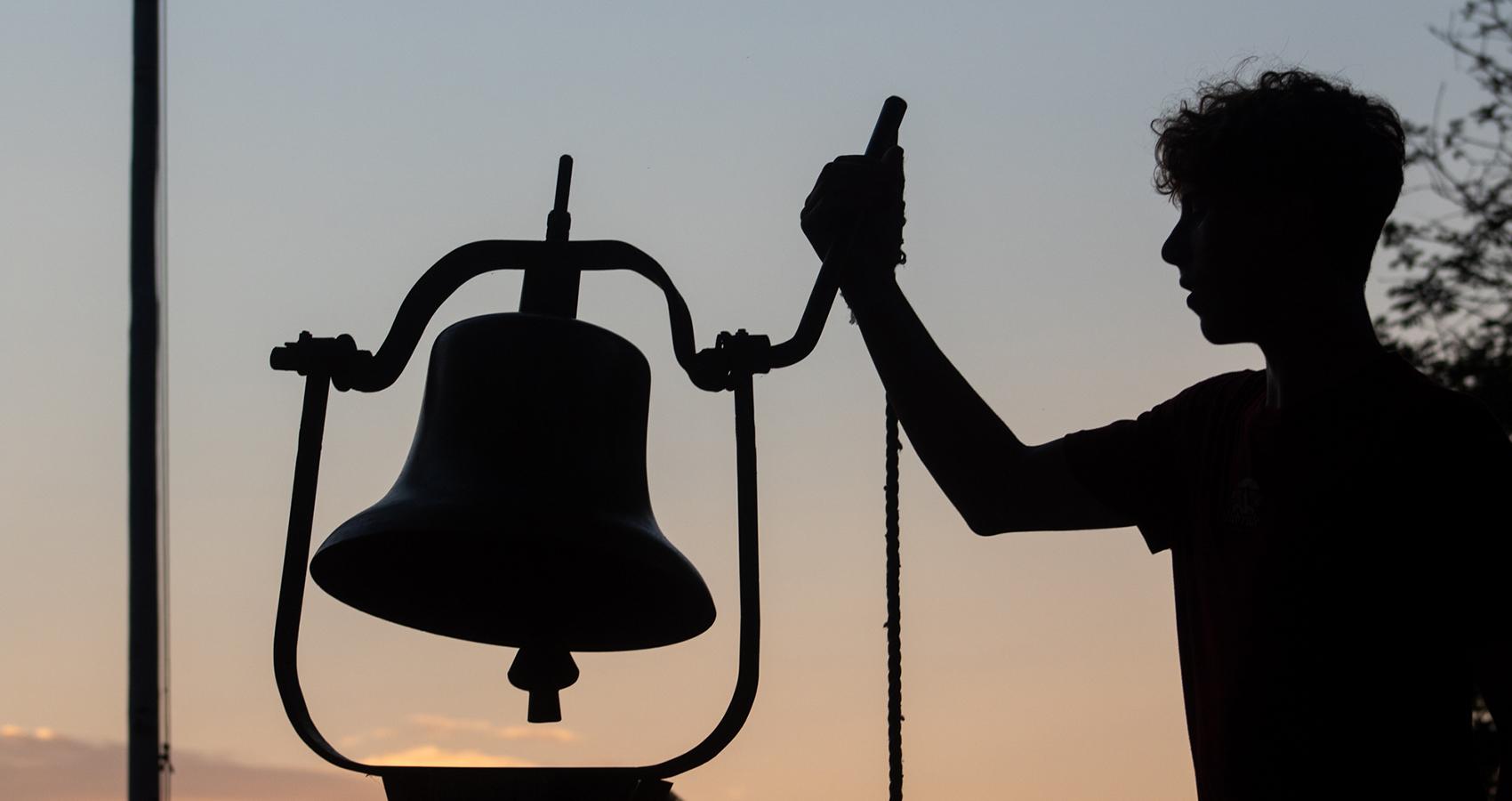 camp person ringing bell at dawn