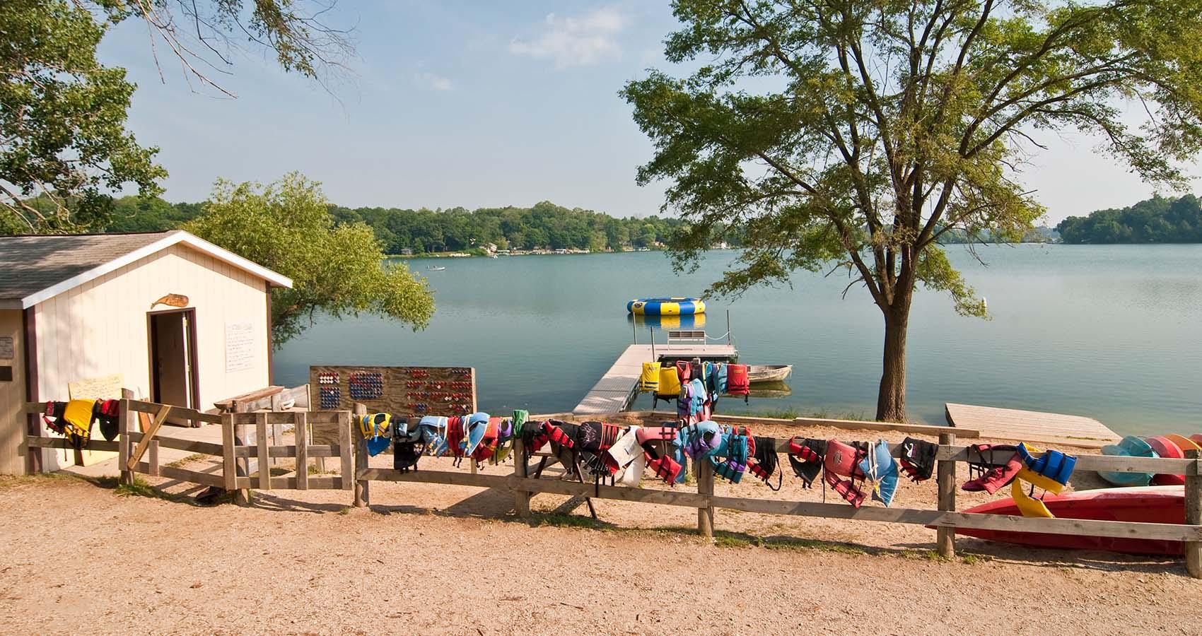 stock photo of lifejackets hanging on fence by lake