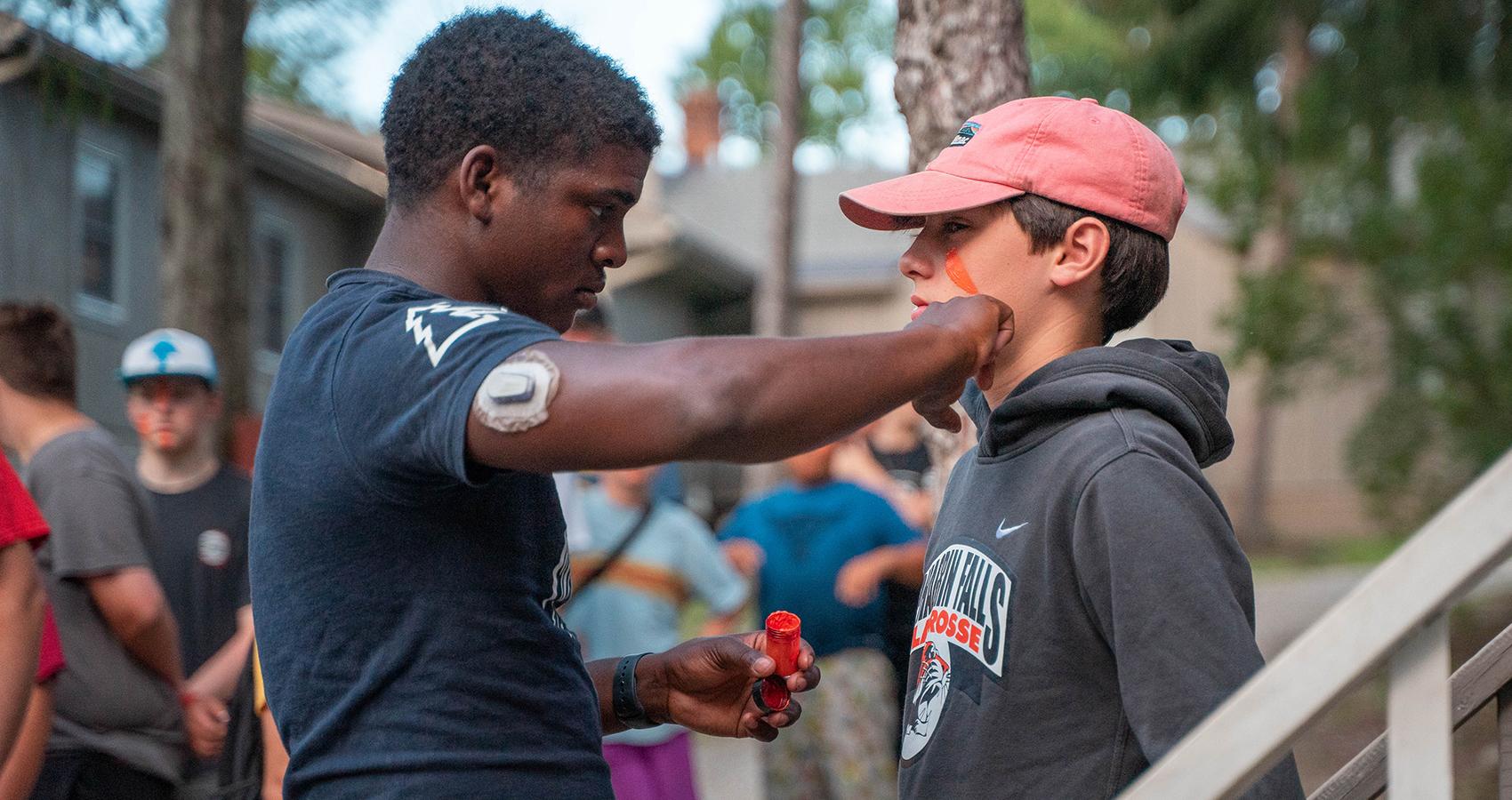 camp staff putting face paint on camper