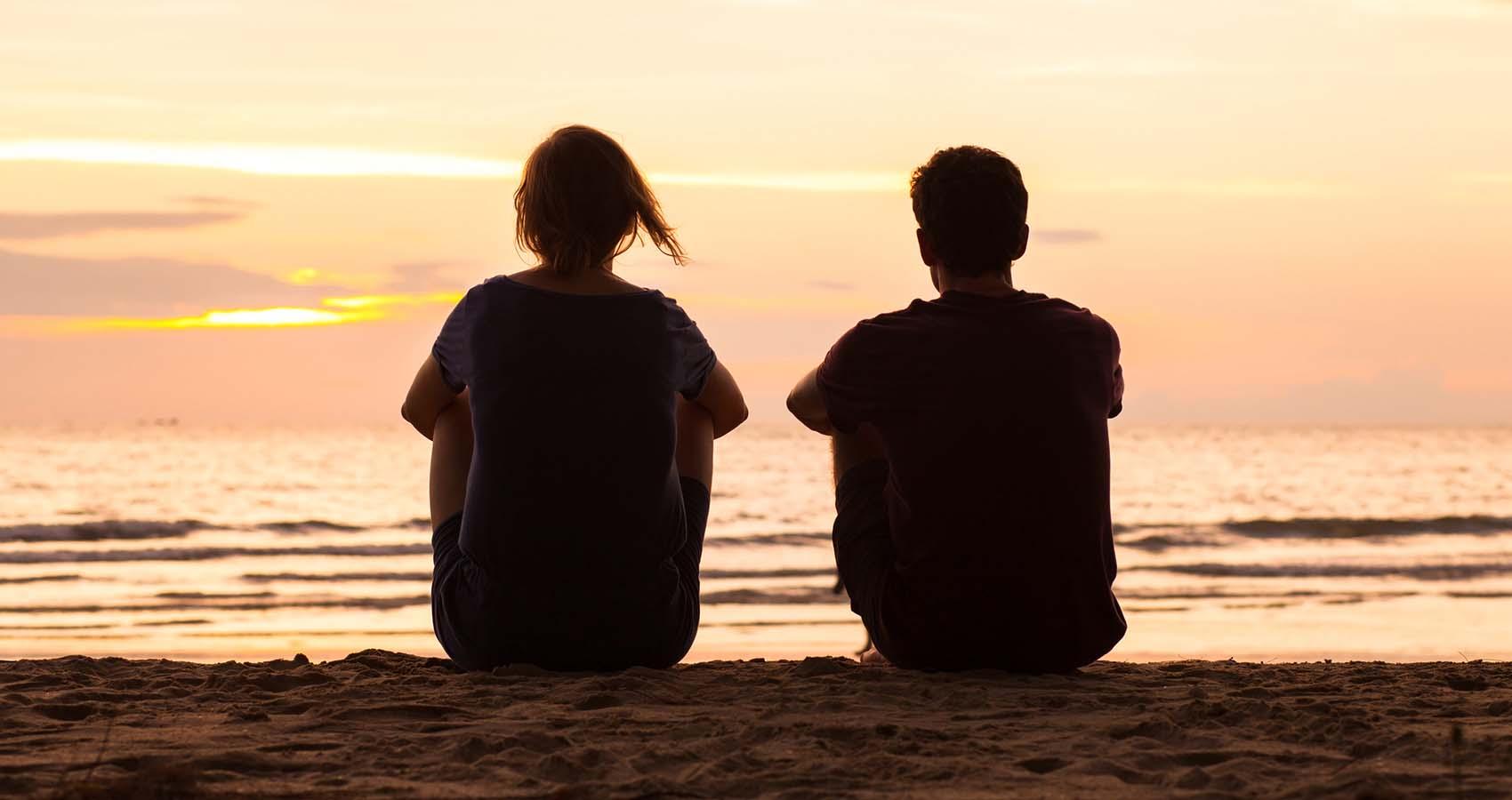 Friends sitting on beach at sunset