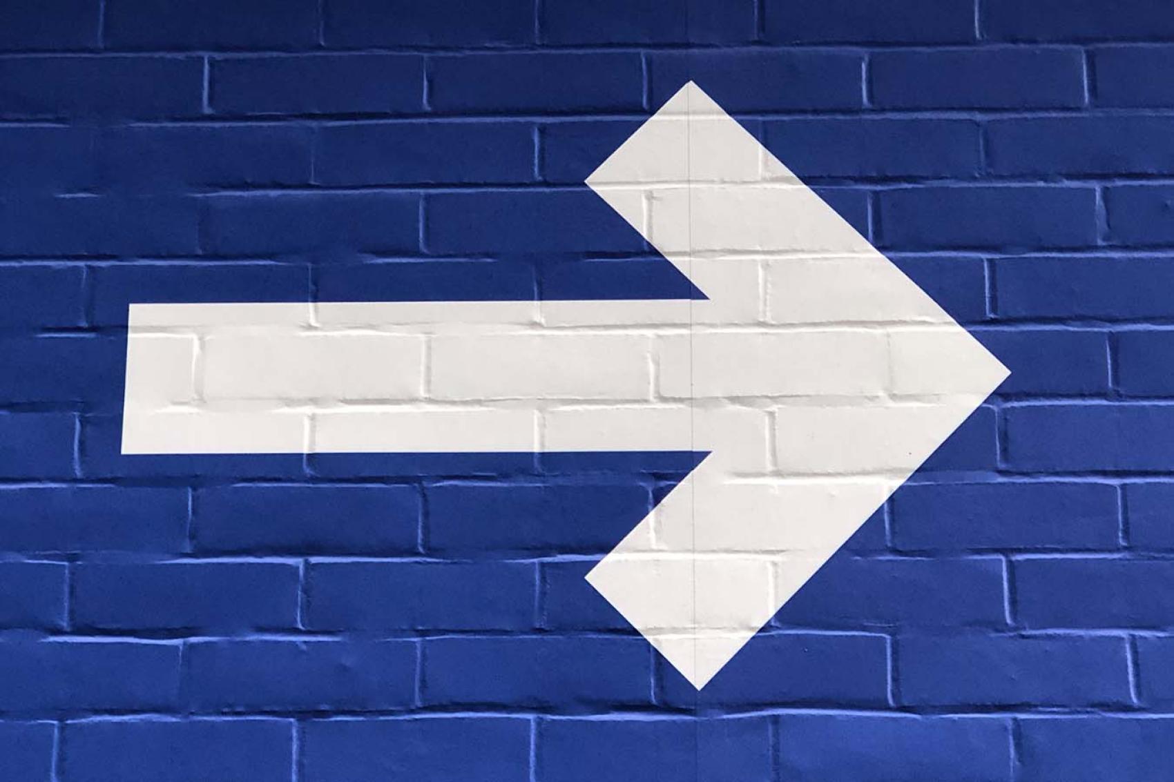 white arrow painted on blue wall