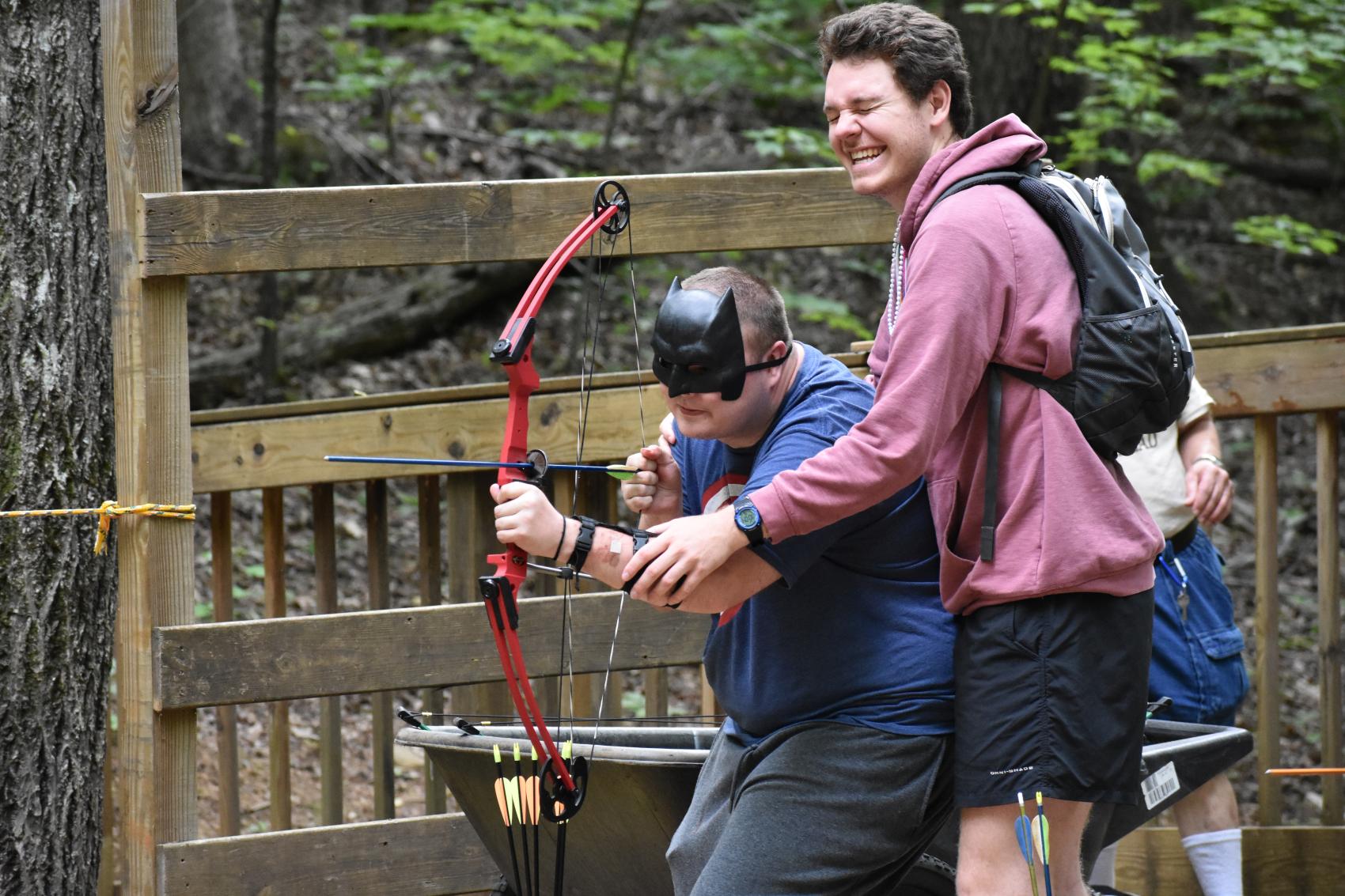 camp staff with camper doing archery