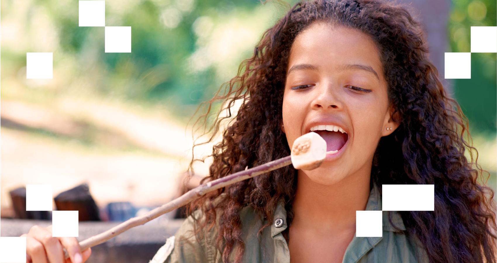 Young child eating marshmallow off stick