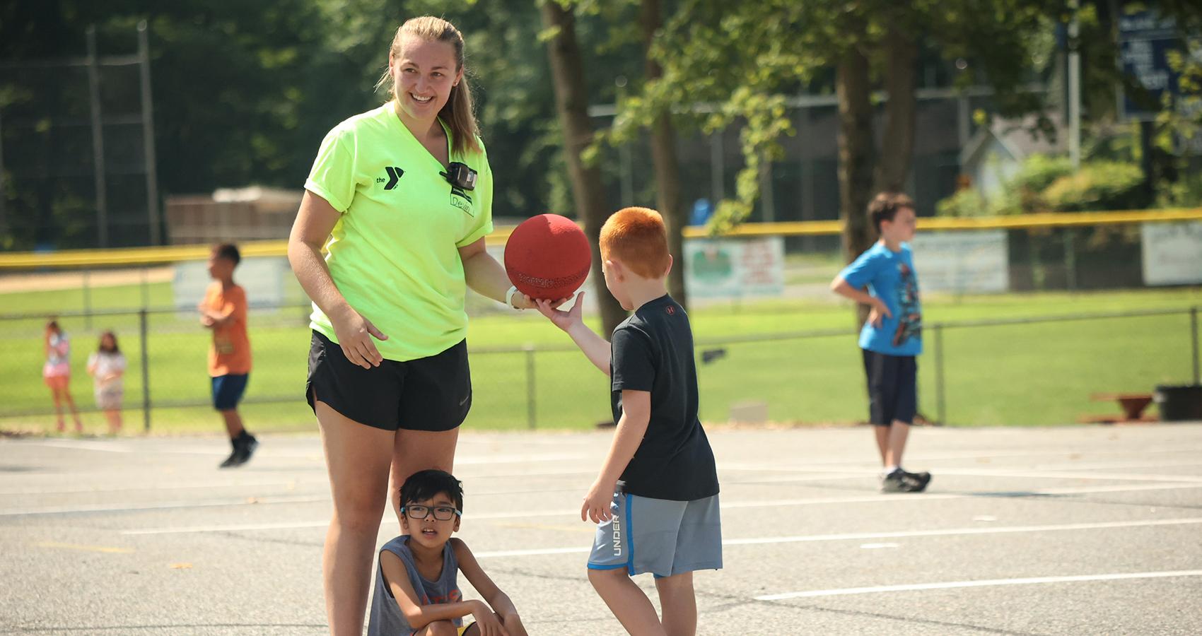 camper handing basketball to camp staff