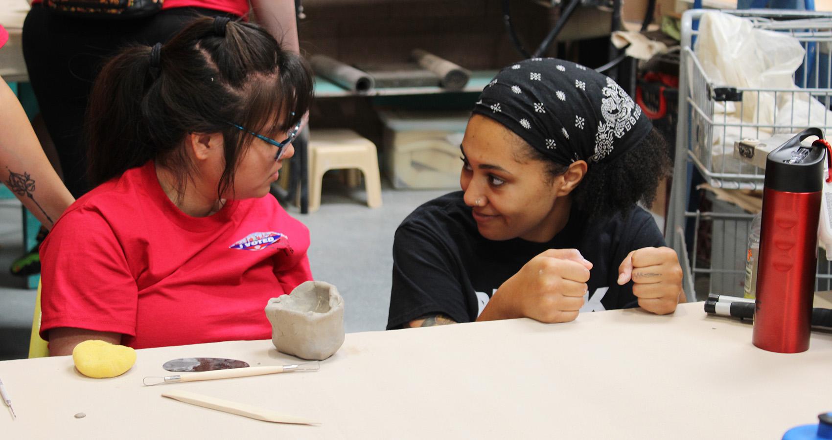 camper and staff doing pottery