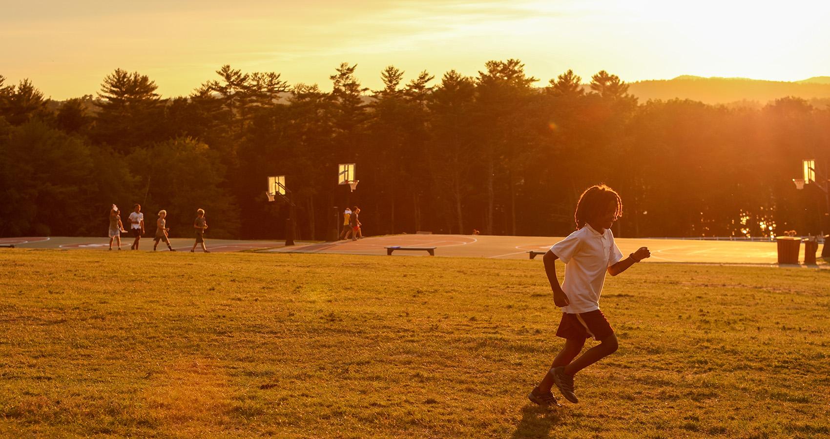 camper running on field with sun setting