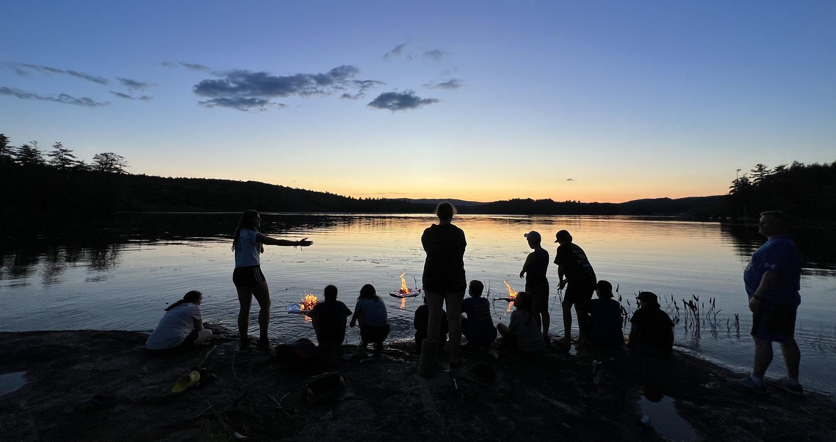 campers and staff around fires at the lake