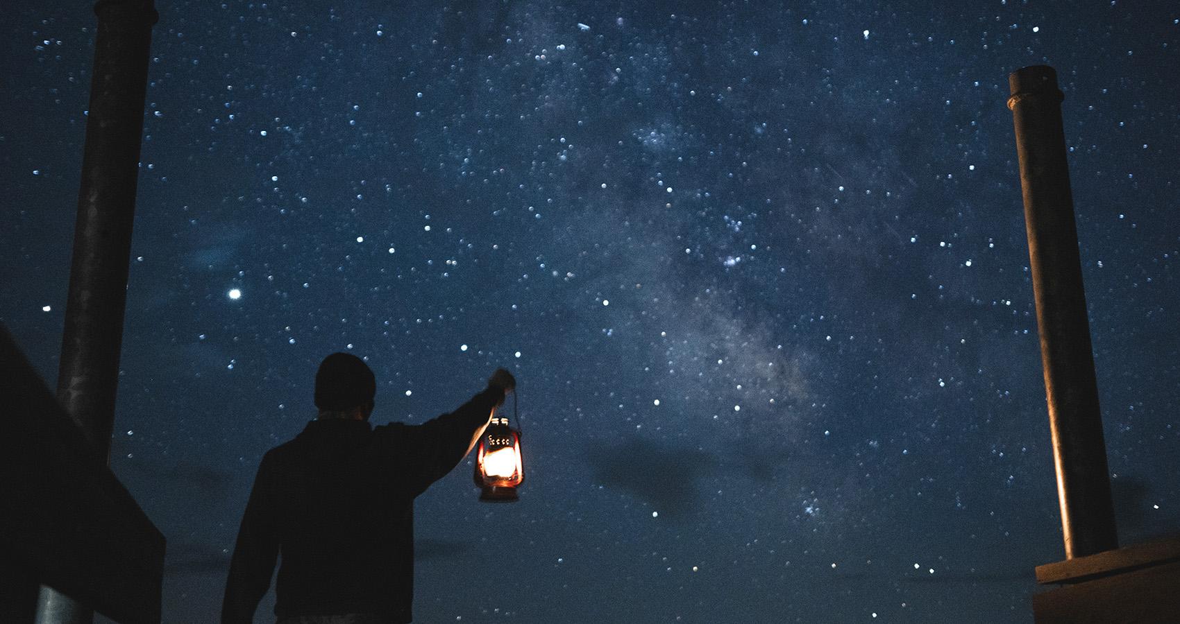 Person holding lantern with starry night sky