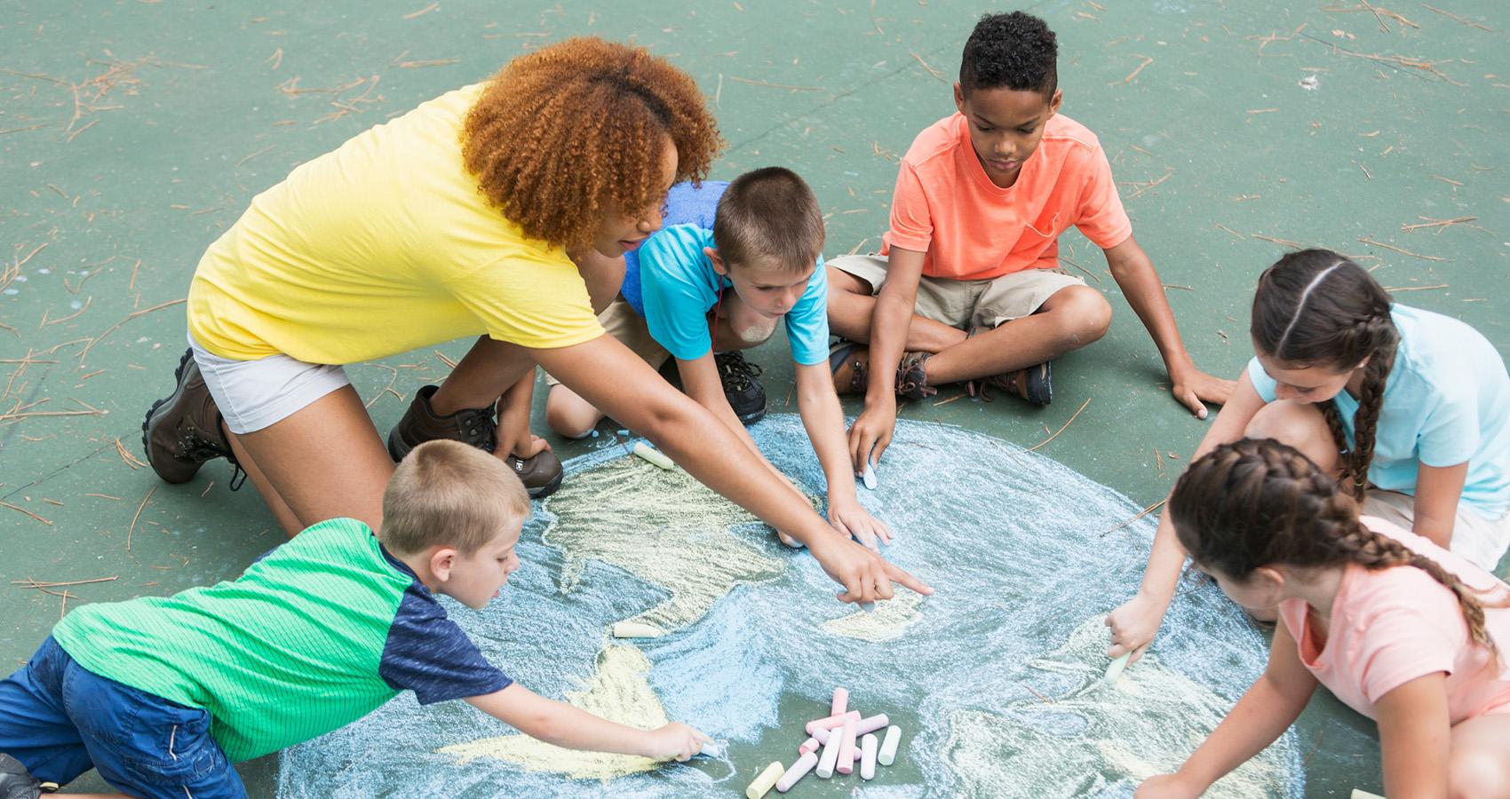 adult helping kids draw with sidewalk chalk