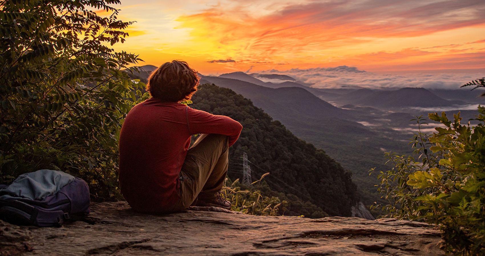 person sitting on rock watching sunset