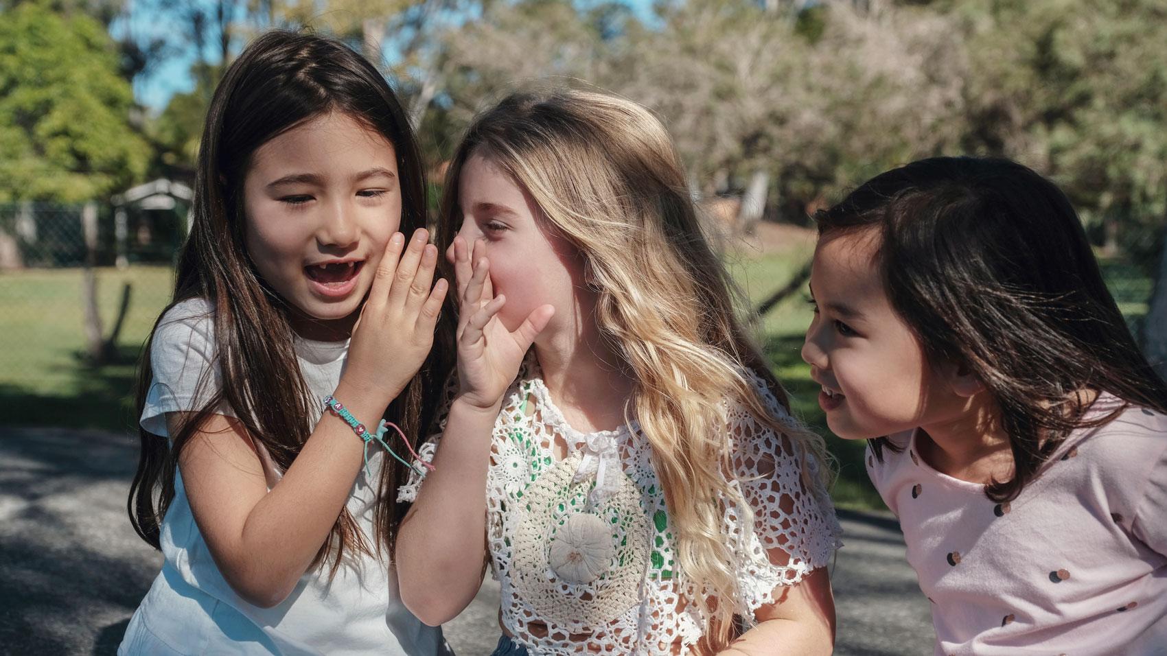 young child whispering into another child's ear