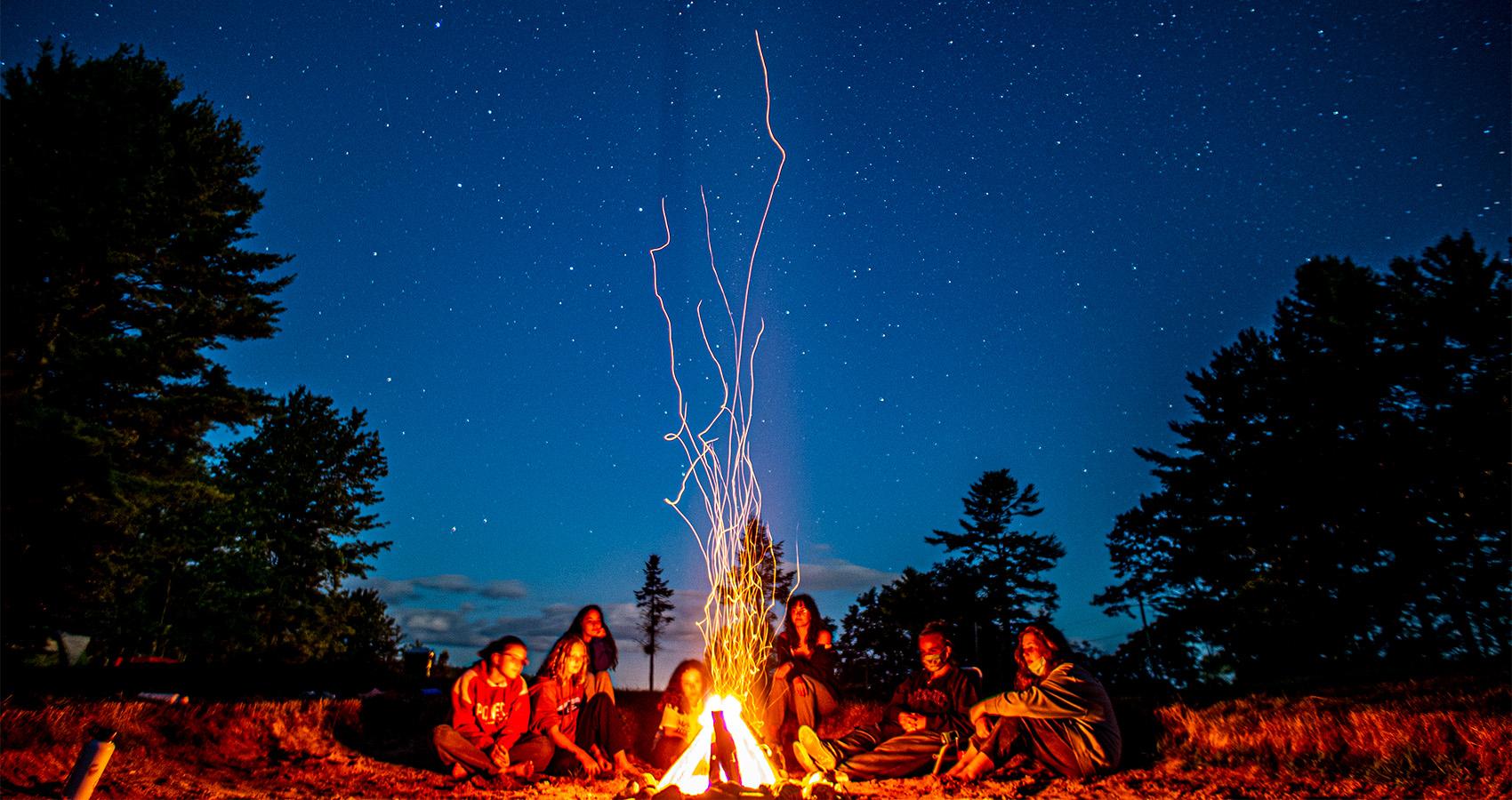 campers sitting around campfire