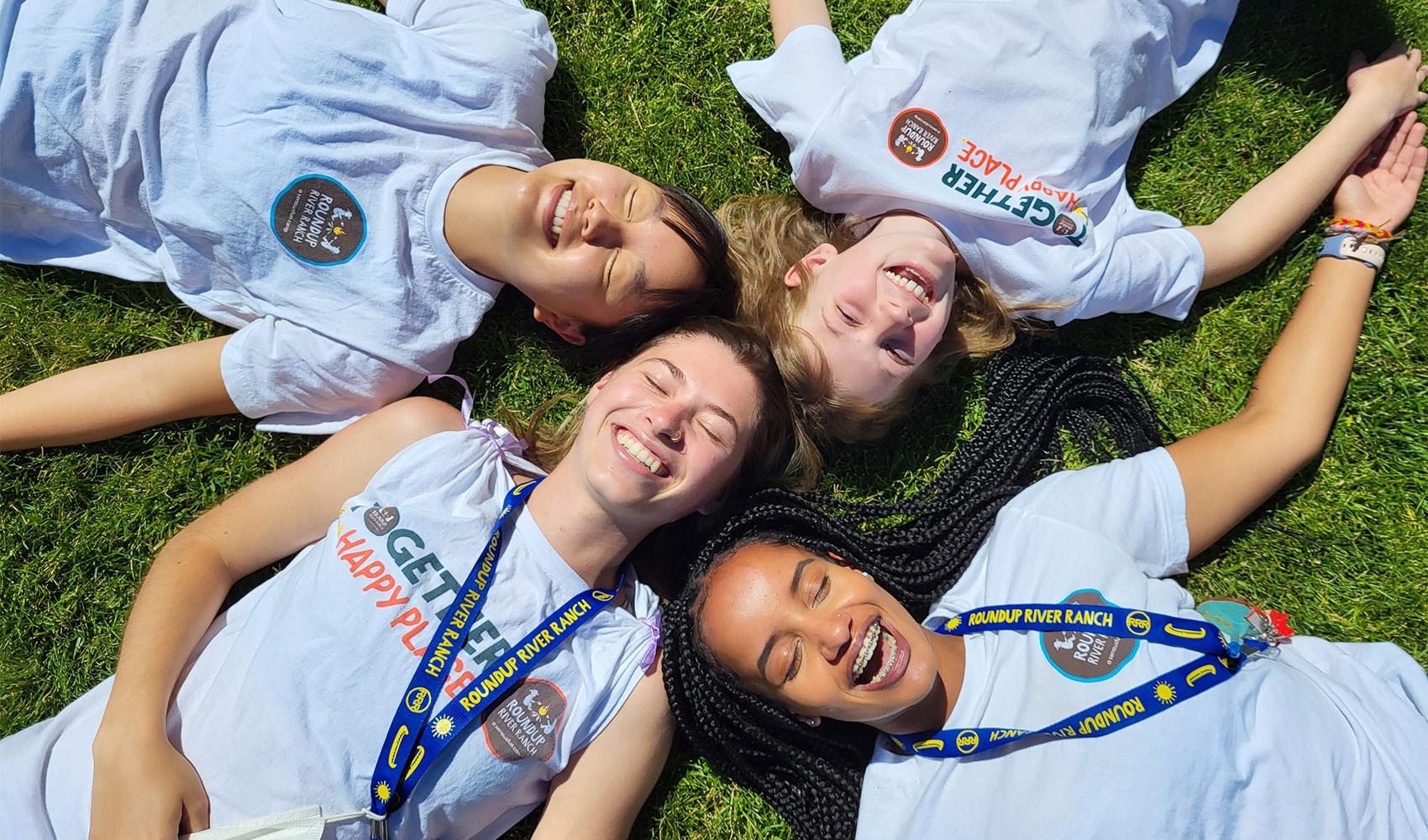 smiling camper friends laying on grass