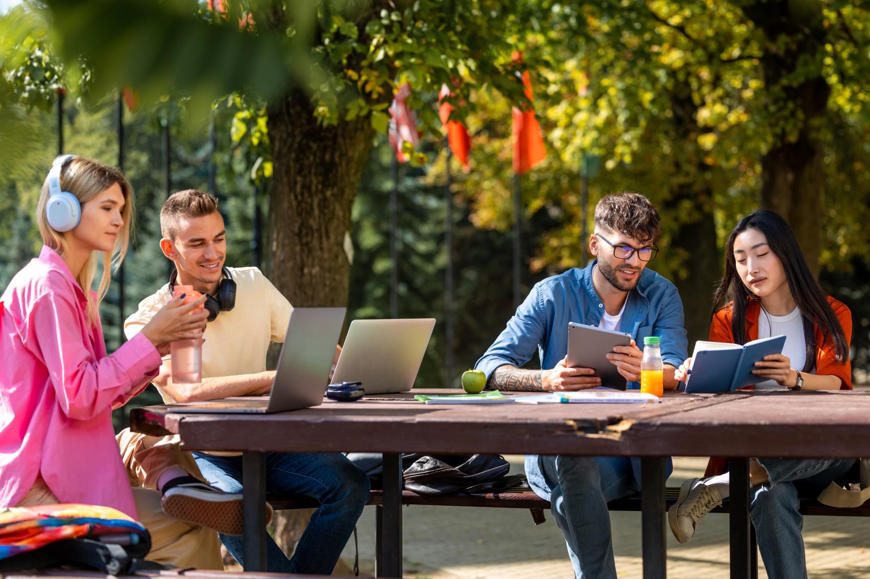young adults learning outdoors on laptops