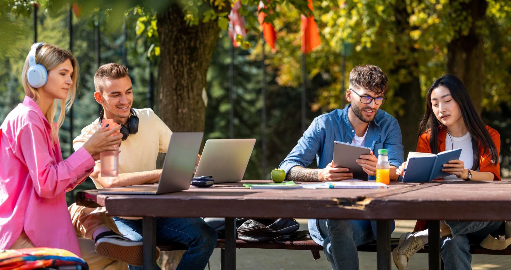 young adults learning outdoors on laptops