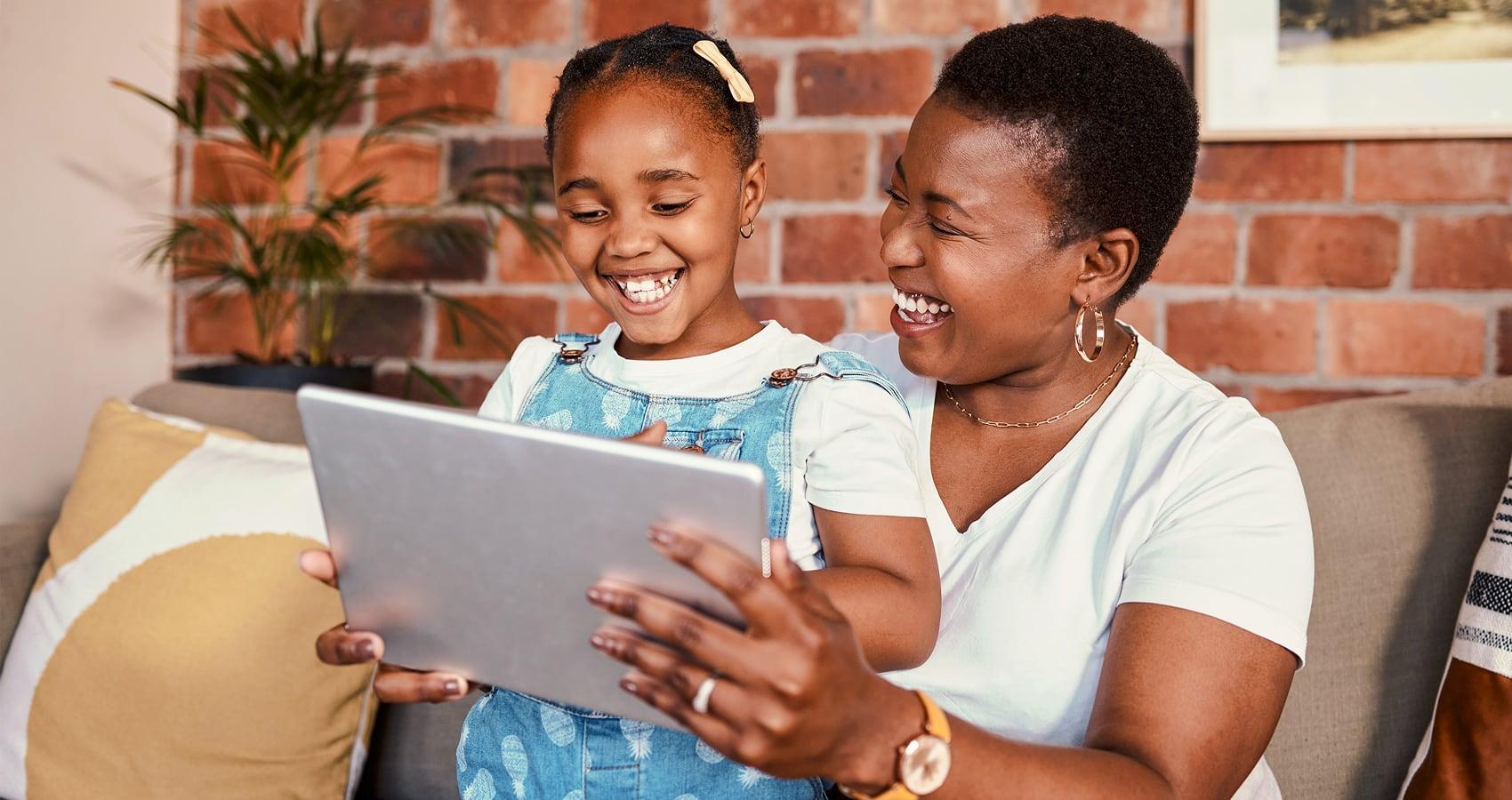 photo of woman and child looking at tablet