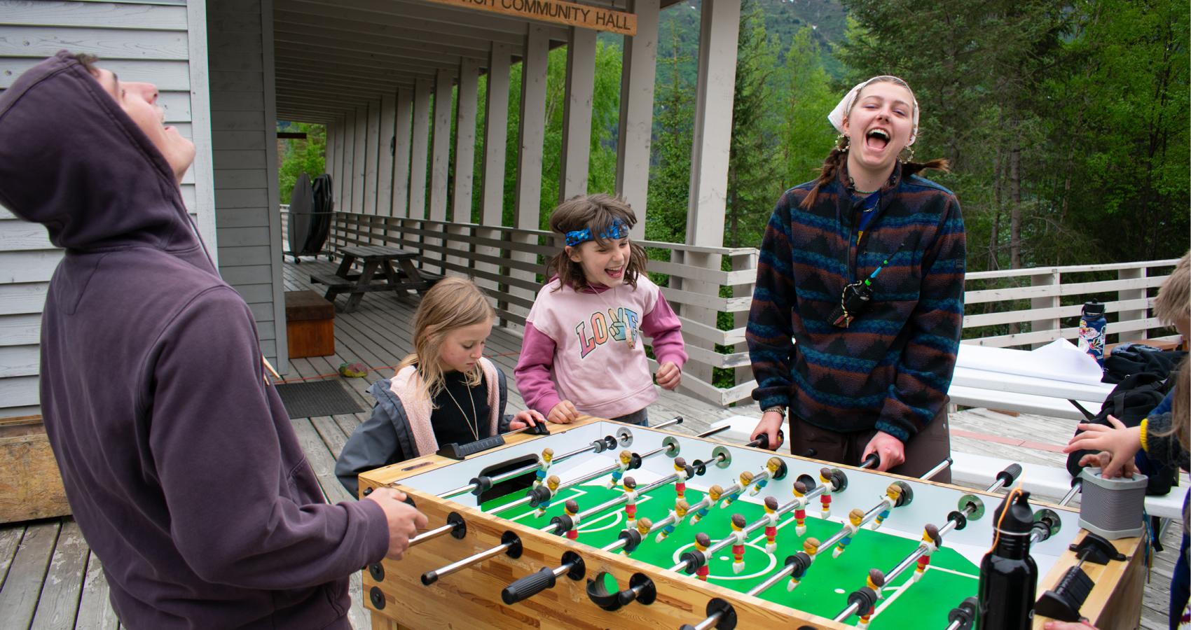 Two counselors playing foosball while two campers watch