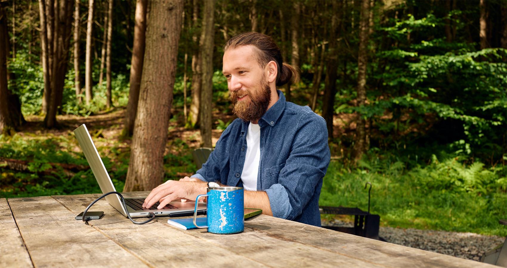 man working on laptop in wooded area