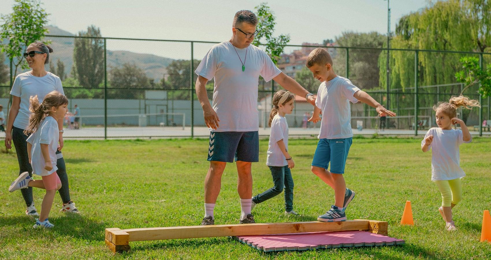 staff helping camper walk across beam