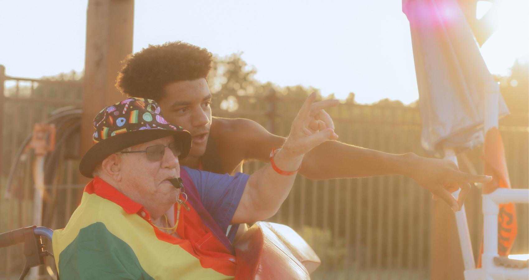 Older camper in a wheelchair pointing at something with a counselor