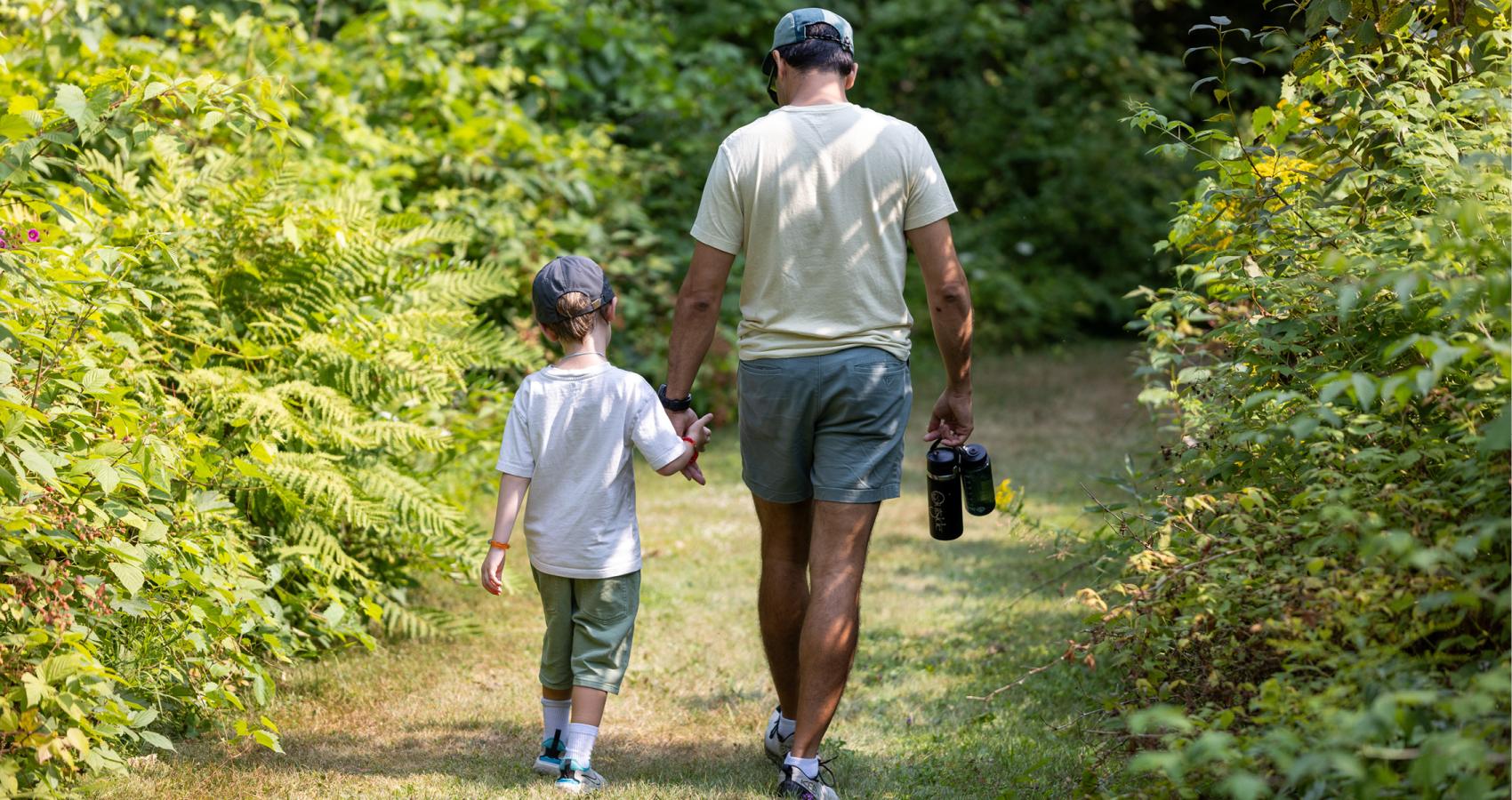 Counselor and Camper walking away in green forest