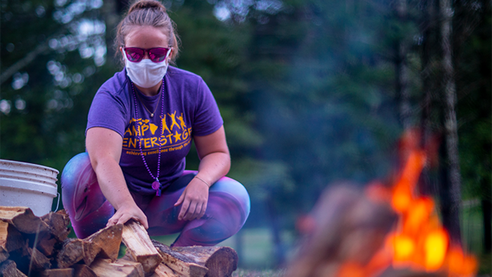 camp staff wearing mask at wood pile