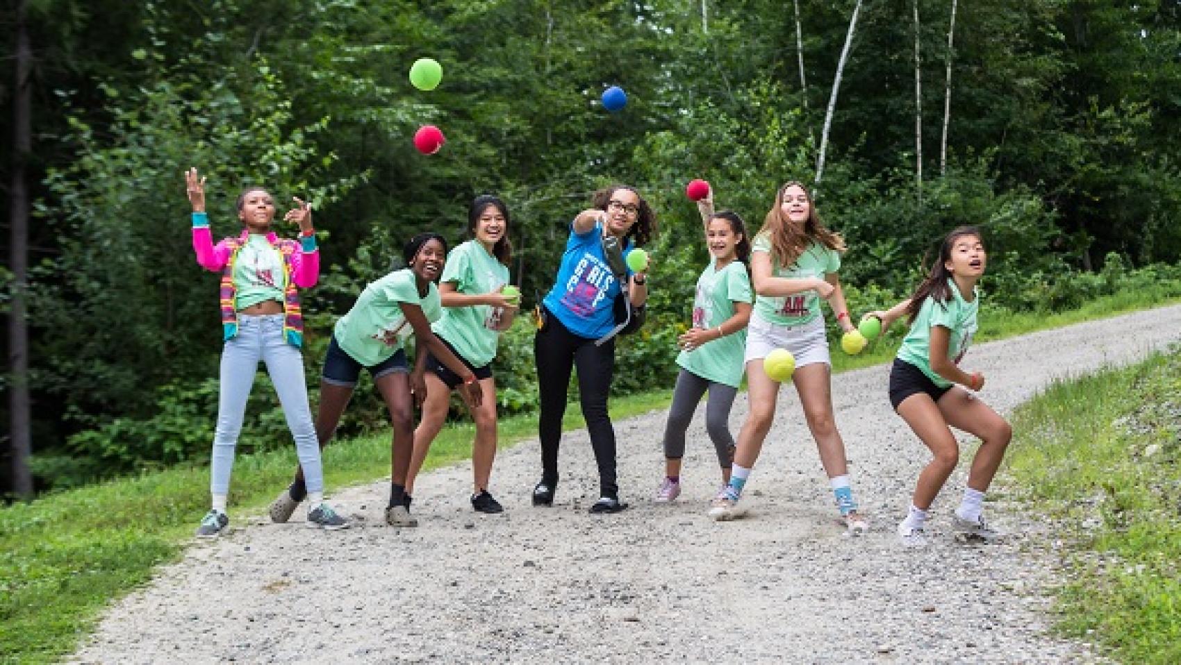 campers and camp staff throw balls toward camera