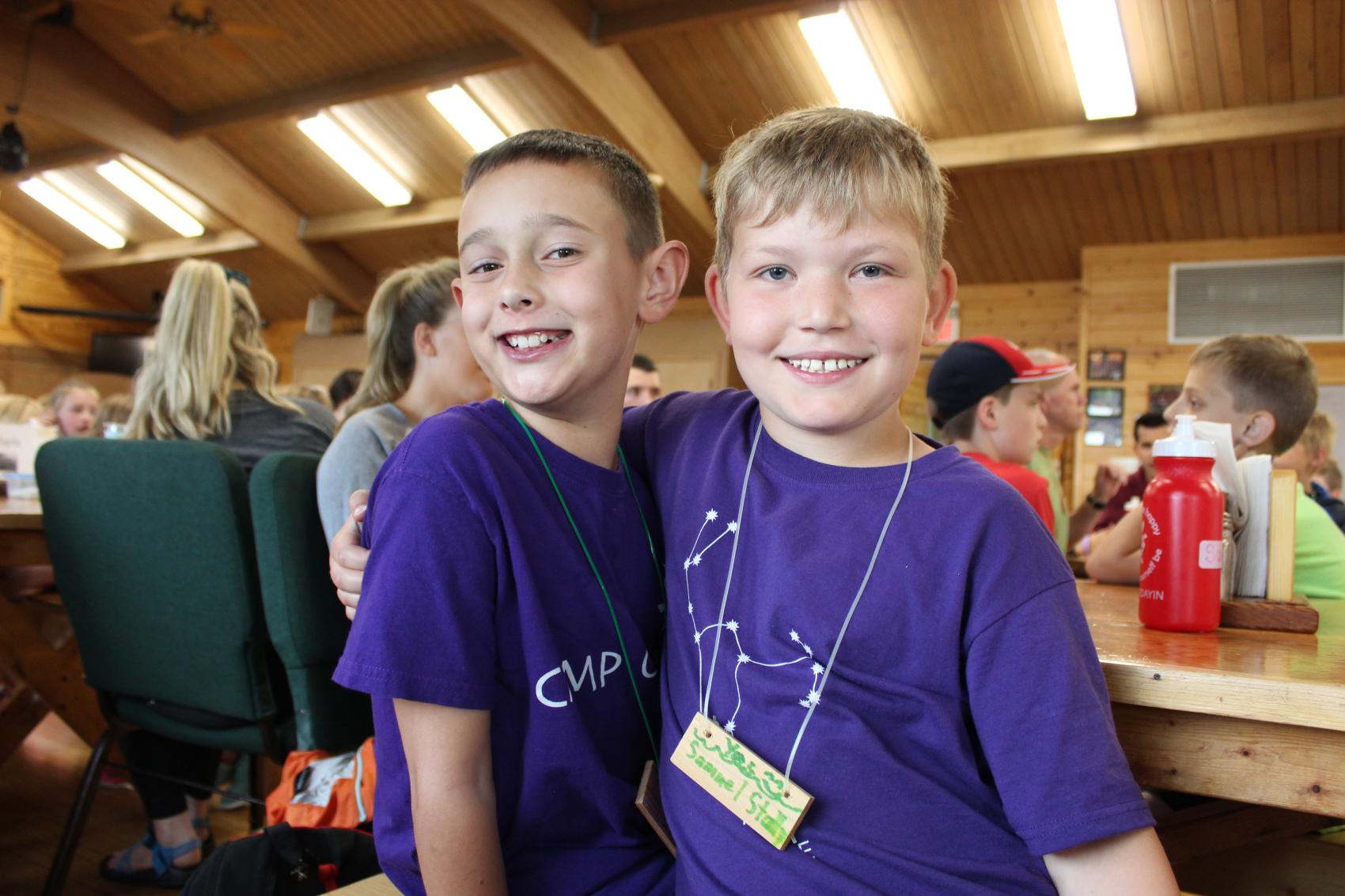 two campers with arms around each other smiling