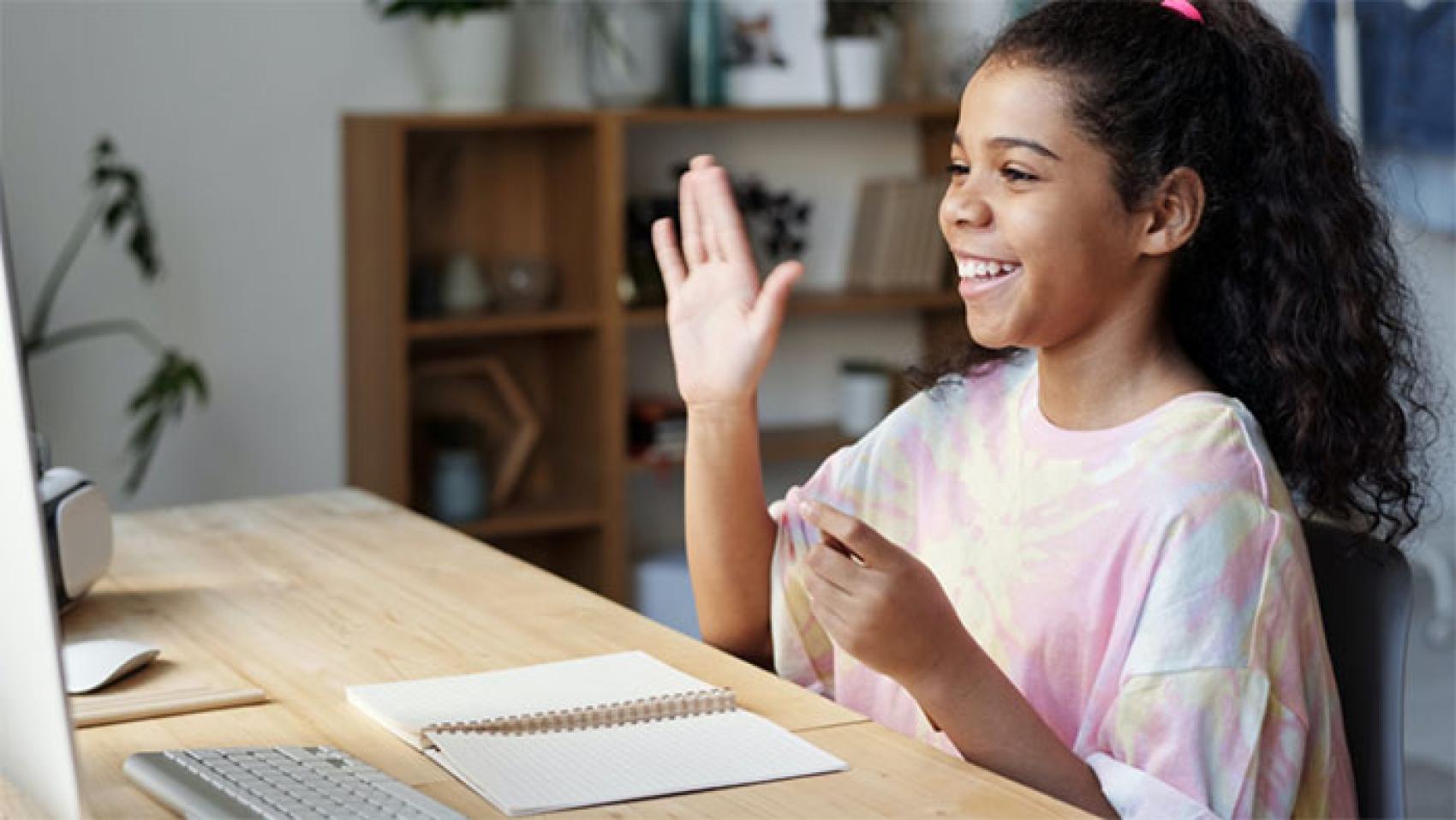 Young girl waving to monitor screen