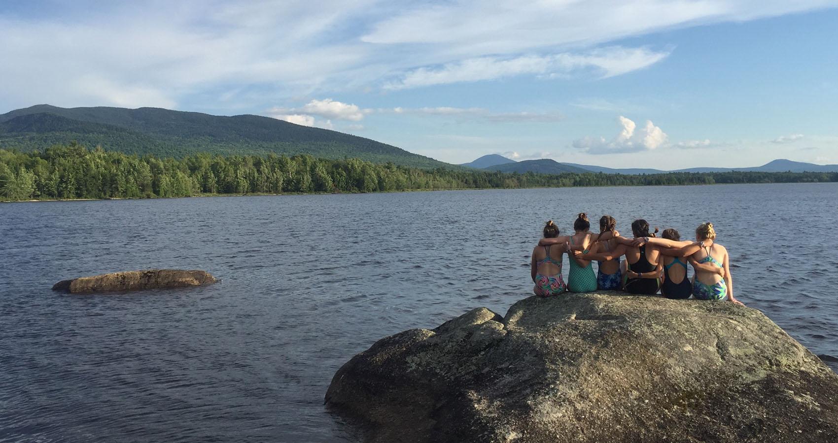 campers sitting on rock looking out over lake