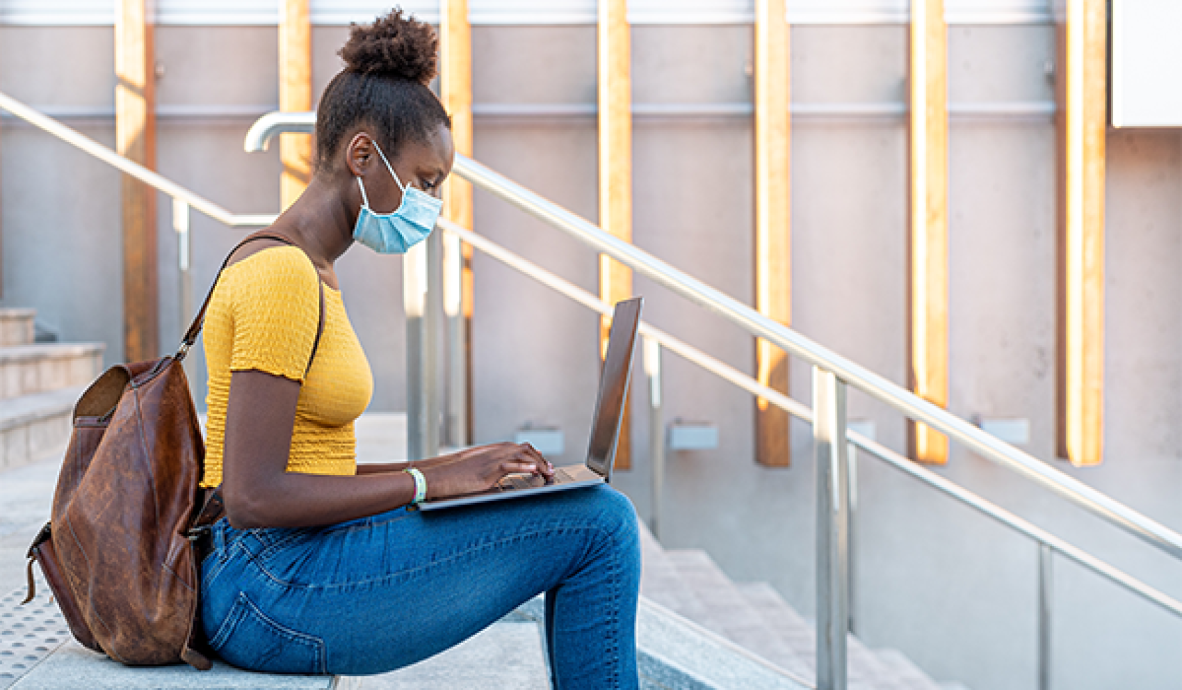 college student wearing mask with laptop