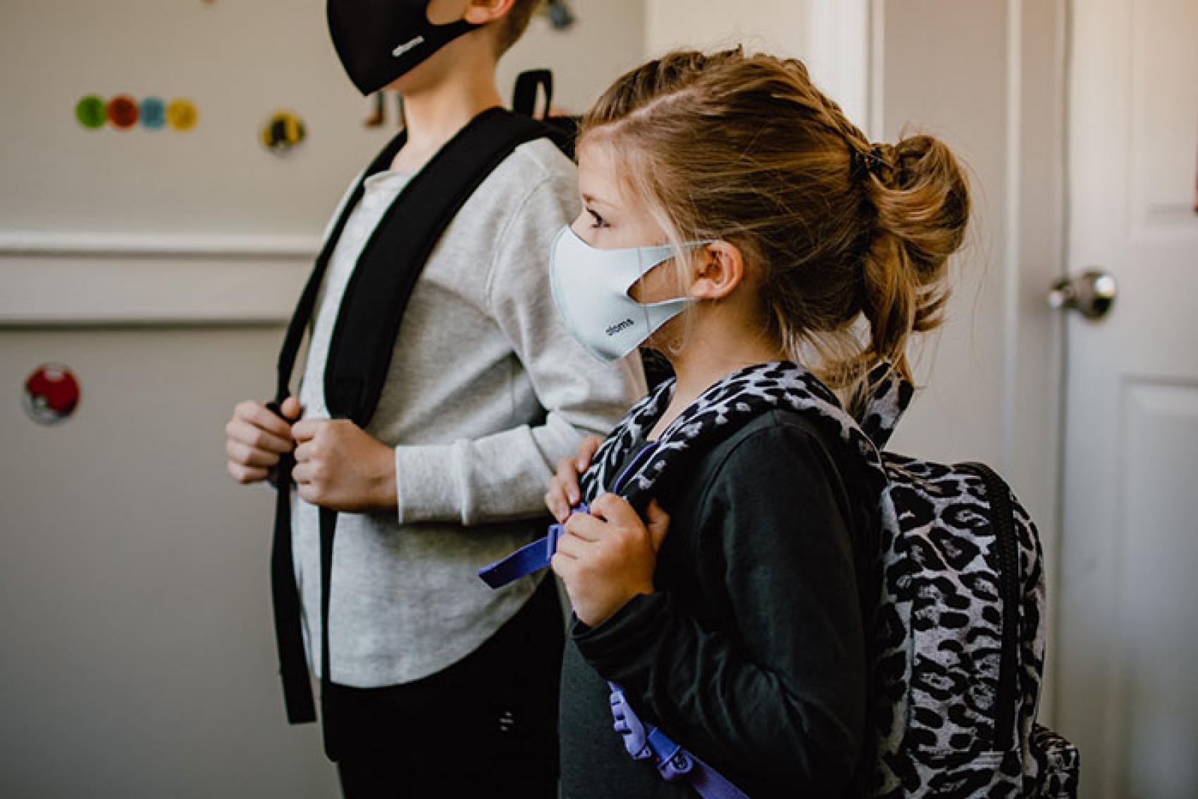 Photo by Kelly Sikkema via Unsplash. Kids wearing masks and backpacks